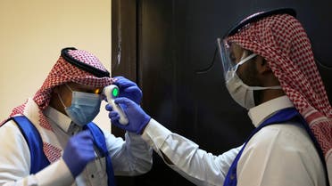 A Saudi volunteer supervisor wearing a protective face mask and gloves checks the temperature of another volunteer before preparing boxes of Iftar meals provided by a charity organisation following the outbreak of the coronavirus disease (COVID-19), during the holy month of Ramadan, in Riyadh, Saudi Arabia May 10, 2020. Picture taken May 10, 2020. REUTERS/Ahmed Yosri