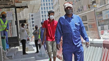 Workers wearing protective masks walk by on a street in Qatar's capital Doha, on May 17, 2020, as the country begins enforcing the world's toughest penalties for failing to wear masks in public, as it battles one of the world's highest coronavirus infection rates. More than 30,000 people have tested positive for COVID-19 in the tiny Gulf country, 1.1 percent of the 2.75 million population, although just 15 people have died. Violators of the new rules will face up to three years in jail and fines of as much as $55,000.