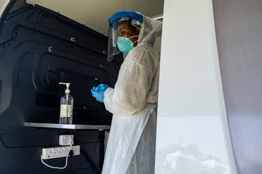 A health worker disinfects her hands as she readies herself for the next patient to be tested at a temporary coronavirus testing station in Diepsloot, Johannesburg on May 8, 2020. (AFP)