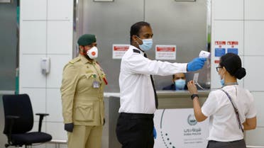 A security man takes temperature of a woman amid the outbreak of the coronavirus disease (COVID-19) at Dubai International Airport, UAE April 27, 2020. Picture taken April 27, 2020. REUTERS/Ahmed Jadallah