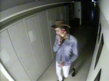 A man is seen speaking on his phone while wearing a cowboy hat he took off a coat rack in the closed Australian Museum in Sydney, Australia, May 10, 2020. (New South Wales Police via Reuters)