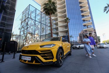 Tourists walk past a luxury rental car parked outside a hotel in Palm Jumeirah in Dubai, United Arab Emirates, March 11, 2020. (Reuters)