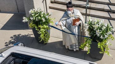 Father Timothy Pelc sprays holy water outside St. Ambrose church in Grosse Pointe Park, Michigan. (Courtesy: Larry Peplin)