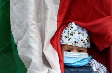 طفل إيطالي يرتدي كمامة ويلتحف بعلم خلال احتجاج في ميلانو