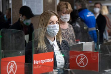 People wearing face masks and gloves to protect against coronavirus, observe social distancing guidelines as they pass through the turnstiles of the subway in Moscow, Russia on May 12, 2020. (AP)