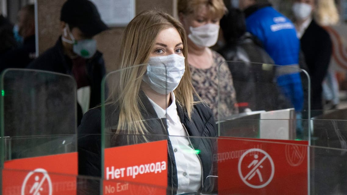 People wearing face masks and gloves to protect against coronavirus, observe social distancing guidelines as they pass through the turnstiles of the subway in Moscow, Russia on May 12, 2020. (AP)