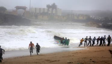 People try to pull back a fishing boat that was carried away by waves on the Arabian Sea coast as others run to take shelter in Veraval, Gujarat, India, on June 13, 2019. (AP)
