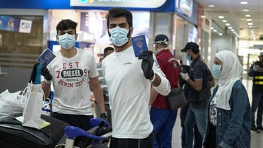 Kuwaiti boys wearing protective face masks and quarantine tracking bracelets, following the outbreak of the coronavirus disease (COVID-19), pose for the camera as they hold up their passports upon arrival from Amman, to Kuwait Airport in Kuwait. (Reuters)