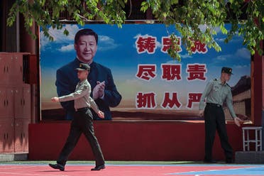 People’s Liberation Army soldiers are seen next to a poster with a picture of Chinese President Xi Jinping next to the entrance to the Forbidden City in Beijing on May 18, 2020. (AFP)