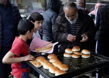 People buy traditional bread at a bakery before the time for iftar, or breaking fast, on the first day of the holy month of Ramadan, as the spread of the coronavirus disease (COVID-19) continues, in the rebel-held Idlib city, Syria April 24, 2020. (Reuters)