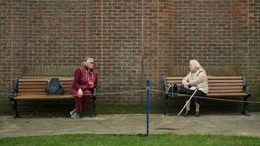 Two women observe social distancing measures as they speak to each other from adjacent park benches in the center of York, northern England on March 19, 2020. (AFP)