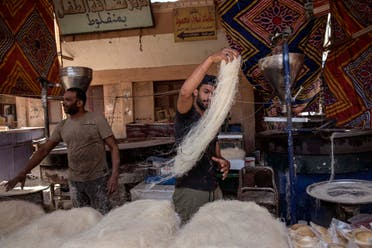 28-year-old football defender Mahrous Mahmoud, right, makes Ramadan sweets at a souq, in Manfalut, Egypt. (AP)
