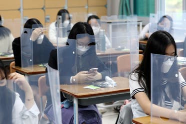 High school students prepare for classes, with plastic covers placed on desks to prevent infection in South Korea. (Reuters)