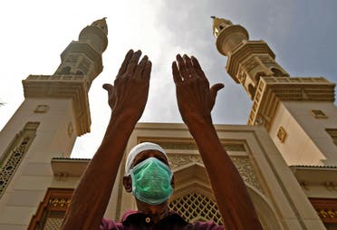 An elderly man wearing a protective mask prays outside a mosque which has been closed to worshipers amid the coronavirus pandemic, in Sharjah, UAE, March 30, 2020. (AFP)
