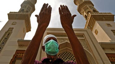 An elderly man wearing a protective mask prays outside a mosque which has been closed to worshipers amid the coronavirus pandemic, in Sharjah, UAE, March 30, 2020. (AFP)
