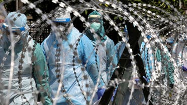 Medical workers wearing protective suits pass by barbed wire at the red zone under enhanced lockdown, amid the coronavirus outbreak in Petaling Jaya, Malaysia May 11, 2020. (Reuters)