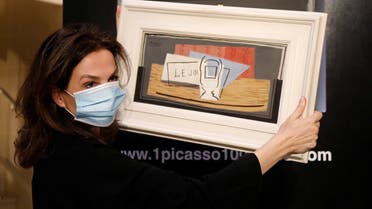 Raffle organizer Peri Cochin, wearing a protective face mask, poses with the painting “Nature Morte, 1921” by Spanish painter Pablo Picasso at Christie’s auction house in Paris, May 20, 2020. (Reuters)