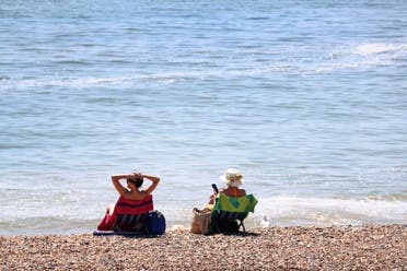 Women enjoy the good weather on the beach as lockdown measures due to the coronavirus outbreak were eased, in Brighton, England, on Thursday May 21, 2020. (AP)