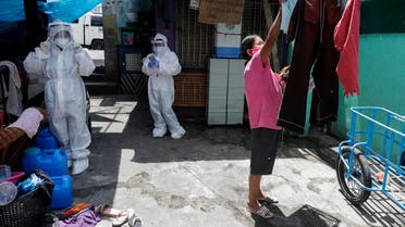 A woman arranges her laundry as health workers wearing protective suits visit a slum area to immunize small children against measles during a quarantine to prevent the spread of coronavirus in Manila, Philippines, May 5, 2020. (AP)