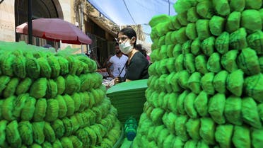 A woman wearing a face mask walks past sweets for sale, ahead of the upcoming holiday of Eid al-Fitr amid concerns over the spread of coronavirus in Sidon, southern Lebanon May 21, 2020. (Reuters)
