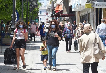 Tunisians walk in the Habib Bourguiba avenue in the capital Tunis on May 12, 2020, following the easing of the lockdown measures to combat the spread of coronavirus. (AFP)