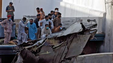 People stand next to the debris of a plane after crashed in a residential area near an airport in Karachi. (Reuters)