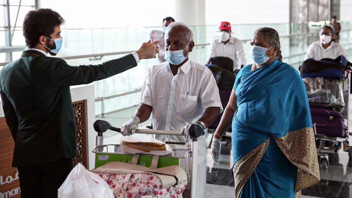 Indian nationals residing in Oman, wearing face masks due to the COVID-19 coronavirus pandemic, have their body temperatures measured at a terminal in Muscat International Airport ahead of their repatriation flight from the Omani capital, on May 12, 2020.