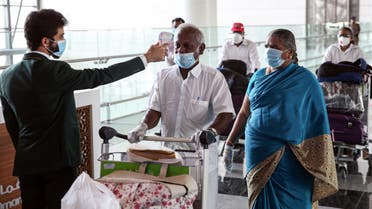 Indian nationals residing in Oman, wearing face masks due to the COVID-19 coronavirus pandemic, have their body temperatures measured at a terminal in Muscat International Airport ahead of their repatriation flight from the Omani capital, on May 12, 2020. 