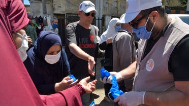 Algerians receive masks distributed by volunteers from the civil society, in a neighbourhood of the capital Algiers on May 21, 2020, as the threat of infections by the COVID-19 caused by the novel coronavirus lingers in the country. 