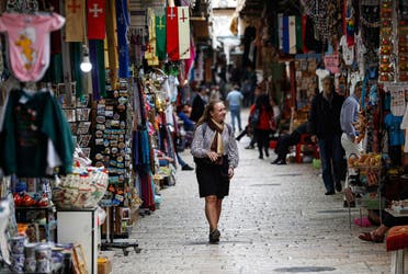 A lone tourist makes her way along a market street in the nearly deserted Old City of Jerusalem on March 12, 2020. (AFP)