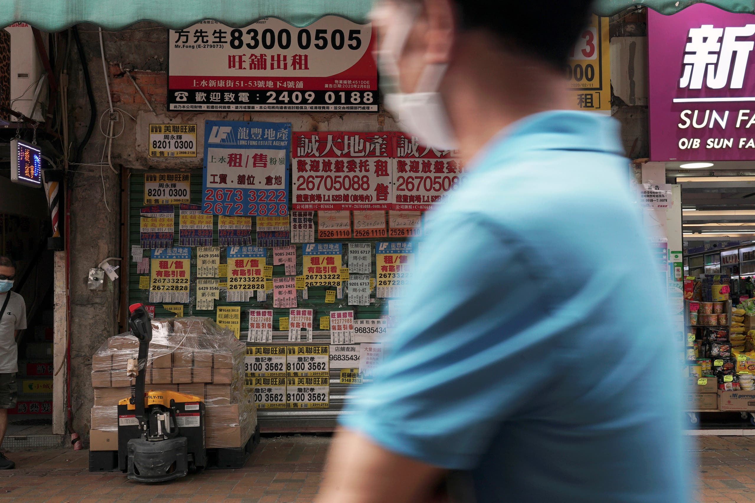 A man wearing a face mask walks past a shuttered shop space covered in rental advertisements, after the border between Shenzhen and Hong Kong was shut due to the coronavirus disease (COVID-19) outbreak, in Hong Kong's northern town of Sheung Shui, China May 18, 2020. (Reuters)