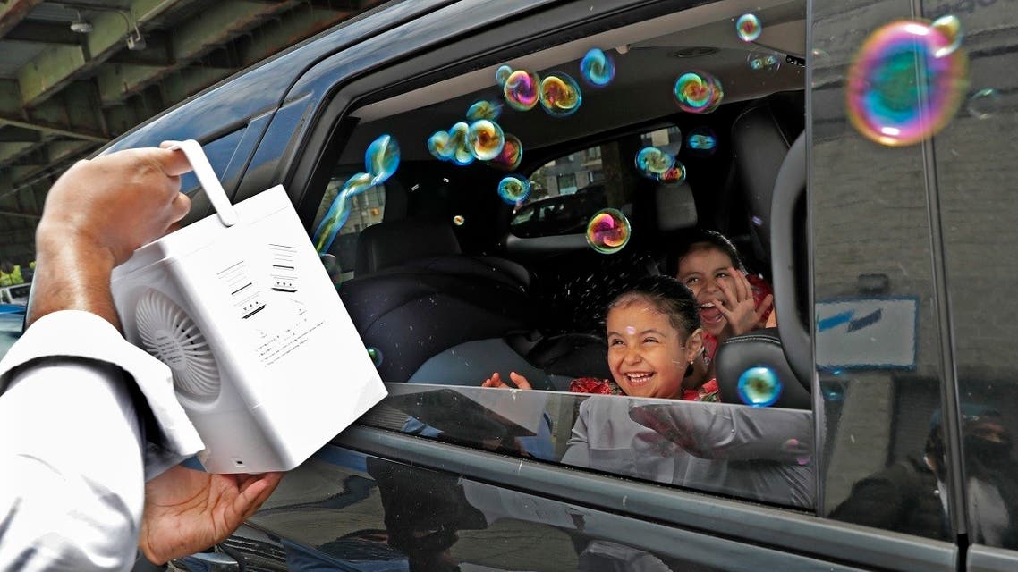 Children react from inside their family’s car as a volunteer from the Muslim Community Center blows bubbles at them as part of an Eid al-Fitr celebration in Brooklyn, May 24, 2020, in New York. (AP)