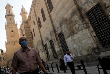 A man wearing a protective face mask walks next to others in front of closed mosques in old Cairo, Egypt. (Reuters)
