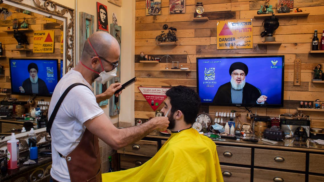 A barber wearing a mask listens to a speech by Hezbollah leader Hassan Nasrallah in the southern suburb of Beirut, Lebanon, Friday, May 22, 2020. (AP)
