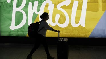 A traveller walks as she carries her bags at Guarulhos International Airport amid the outbreak of the coronavirus disease (COVID-19), in Guarulhos, near Sao Paulo, Brazil. (Reuters)