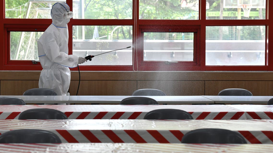 A health official wearing protective gear sprays disinfectant in a cafeteria at a high school in Seoul on May 11, 2020 as schools are set to re-open starting this week. South Korea announced its highest number of new coronavirus cases for more than a month on May 11, driven by an infection cluster in a Seoul nightlife district just as the country loosens restrictions.