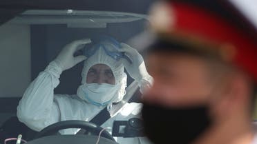 A specialist wearing protective gear and a law enforcement officer with a face mask are seen upon the arrival of a plane carrying Kyrgyz citizens, who came from Japan and South Korea amid the outbreak of the coronavirus disease (COVID-19), at an airport in Almaty, Kazakhstan May 14, 2020. REUTERS/Pavel Mikheyev
