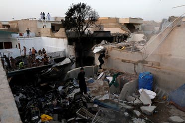 People stand on a roof of a house amidst debris of a passenger plane, crashed in a residential area near an airport in Karachi, Pakistan May 22, 2020. (Reuters)