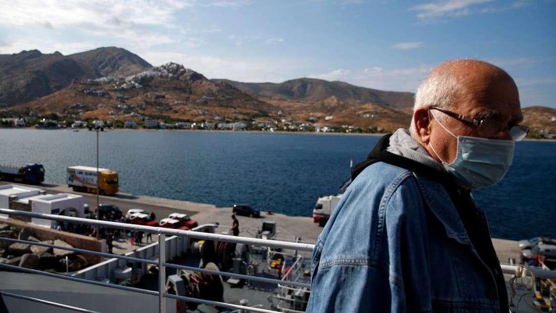 A passenger wearing a face mask to prevent the spread of the new coronavirus, stands on the deck of a ferry as it approaches the Aegean Sea island of Serifos, Greece, on Tuesday, May 26, 2020. Greece restarted regular ferry services to its islands Monday, and cafes and restaurants were also back open for business as the country accelerated efforts to salvage its tourism season. (AP Photo/Thanassis Stavrakis)
