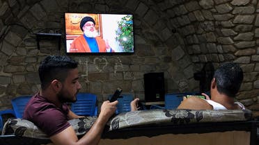 Men hold their phones as they watch Lebanon's Hezbollah leader Sayyed Hassan Nasrallah speak on television inside a coffee shop in the port city of Sidon, Lebanon July 12, 2019. (Reuters)