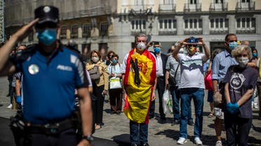 People hold a minute of silence for the victims of COVID-19 at Sol square in downtown Madrid, Spain, Wednesday, May 27, 2020. Flags are flying at half-mast on more than 14,000 public buildings in Spain as the European nation holds its first of 10 days of national mourning for the victims of the coronavirus. (AP Photo/Manu Fernandez)
