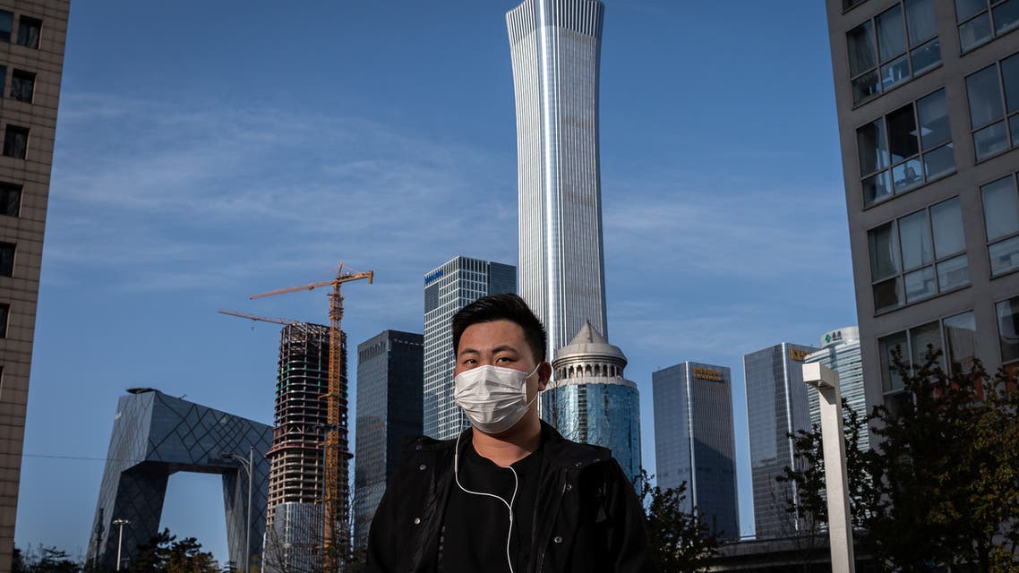 A man wearing a face mask amid the COVID-19 coronavirus outbreak walks outside office buildings in Beijing on April 1, 2020. (AFP)
