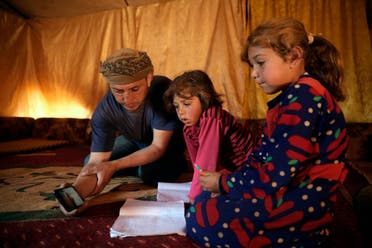 In this April 13, 2020 photo, Tariq al-Obeid, displaced from the eastern countryside of Idlib, Syria, shows a lesson for his children on a mobile phone in Kelly, a town in northern Idlib. (AP)