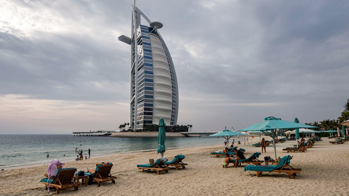 Beach-goers lie on lounge chairs by the shoreline near the Burj al-Arab hotel in Dubai, UAE on May 20, 2020. (AFP)