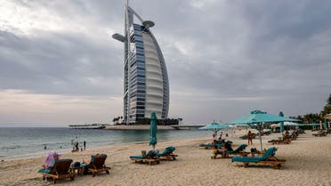 Beach-goers lie on lounge chairs by the shoreline near the Burj al-Arab hotel in Dubai, UAE on May 20, 2020. (AFP)