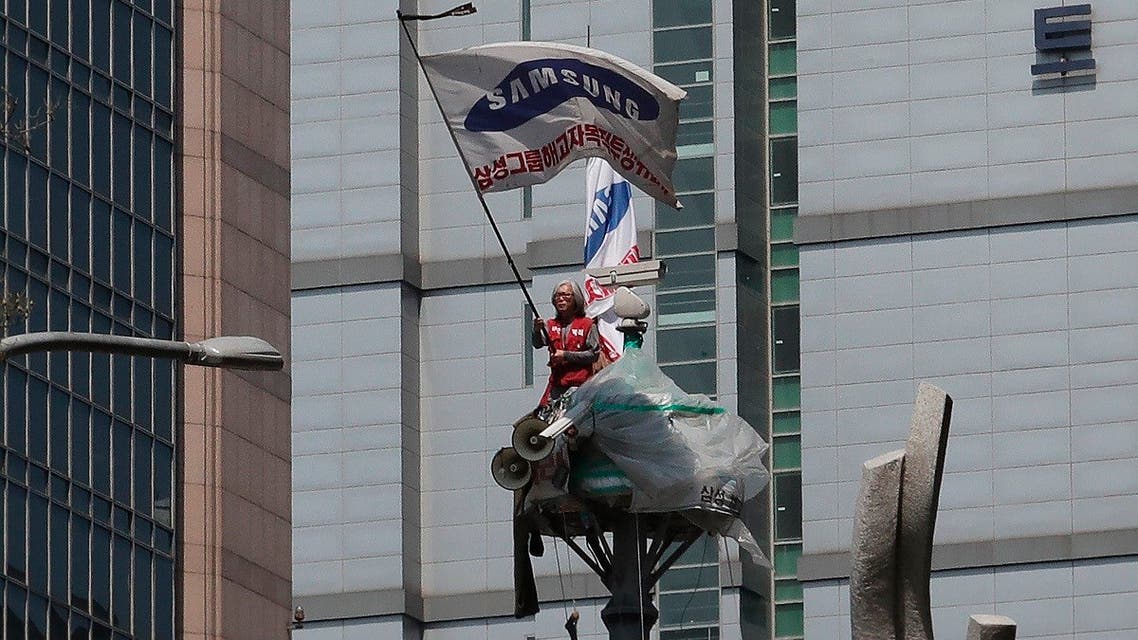 A protester Kim Yong-hee waves a Samsung Group flag against the group's union policy at the top of a traffic camera tower in Seoul, South Korea, Wednesday, May 6, 2020. (AP)