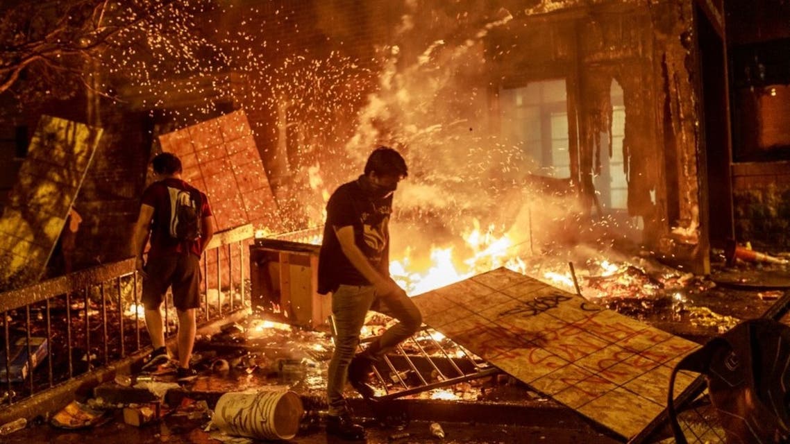 Protesters walk past burning debris outside the Third Police Precinct on May 28, 2020 in Minneapolis, Minnesota, US, during a protest over the death of George Floyd. (AFP)