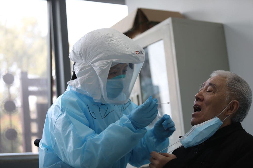 A medical worker takes a swab from a previously recovered COVID-19 patient during testing at a hospital in Wuhan, in China's central Hubei province on March 14, 2020. (AFP)