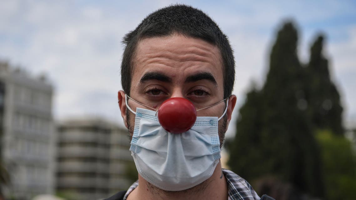 A Greek artist protests wearing a face mask and a red nose in Athens on May 7, 2020. (AFP)