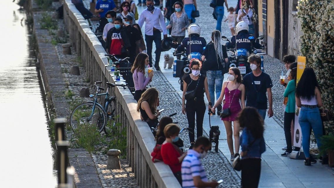 Policemen on motorbikes patrol as people stroll along a canal in the Navigli district of Milan on May 21, 2020 as the country eases its lockdown after over two months. (AFP)